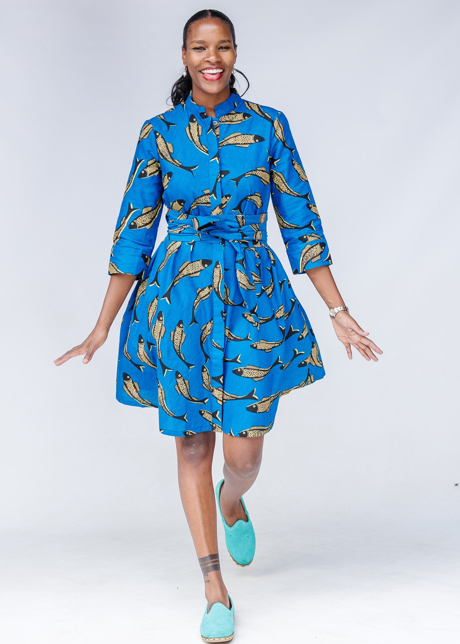 Model wearing blue dress with beige fish print.
