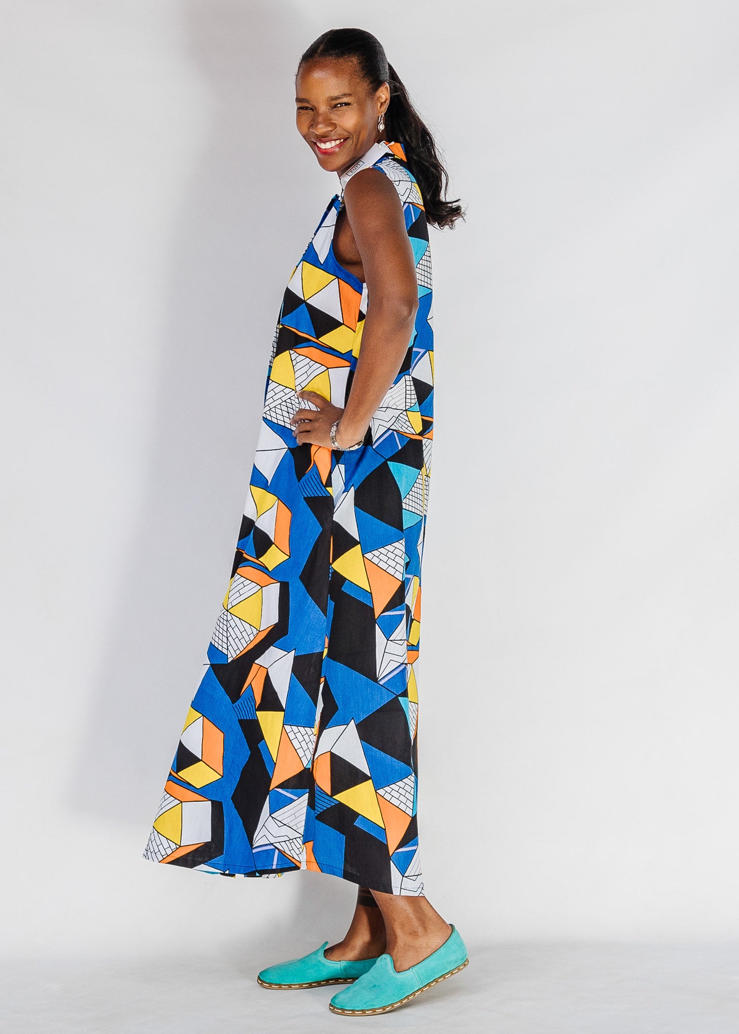 Model wearing blue dress with yellow, black, orange and white geometric print.