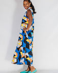 Model wearing blue dress with yellow, black, orange and white geometric print.