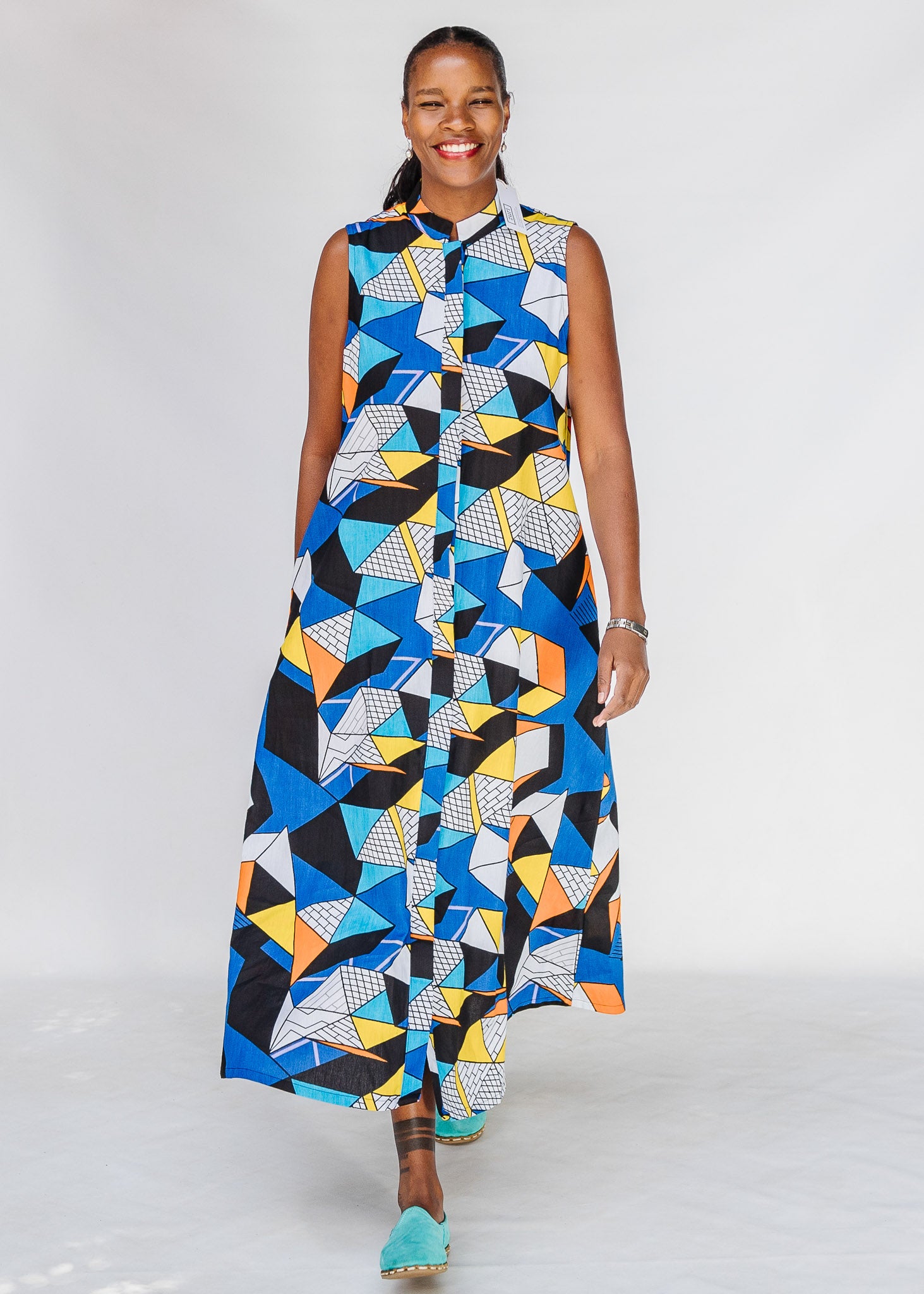 Model wearing blue dress with yellow, black, orange and white geometric print.
