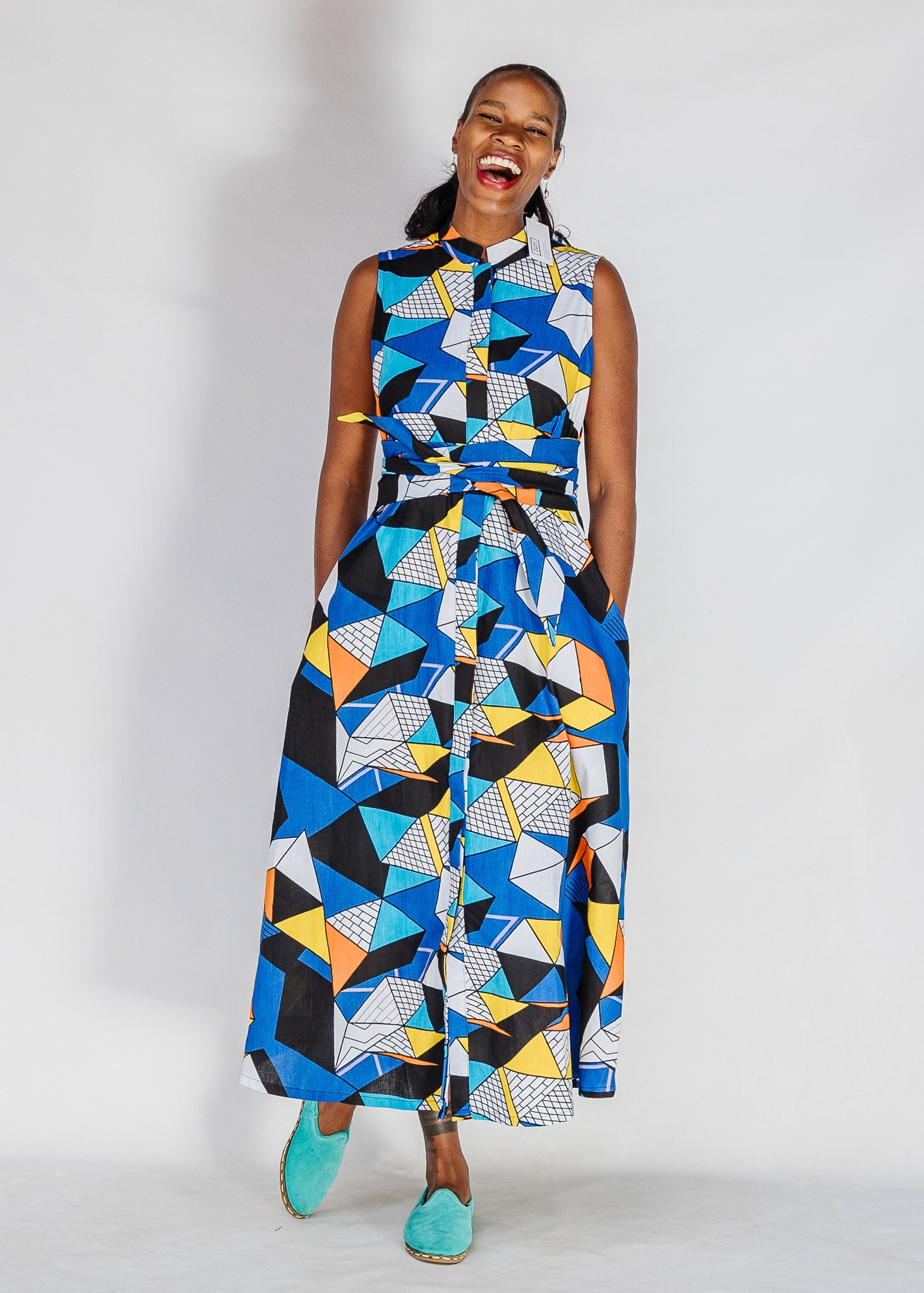 Model wearing blue dress with yellow, black, orange and white geometric print.