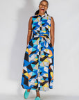 Model wearing blue dress with yellow, black, orange and white geometric print.