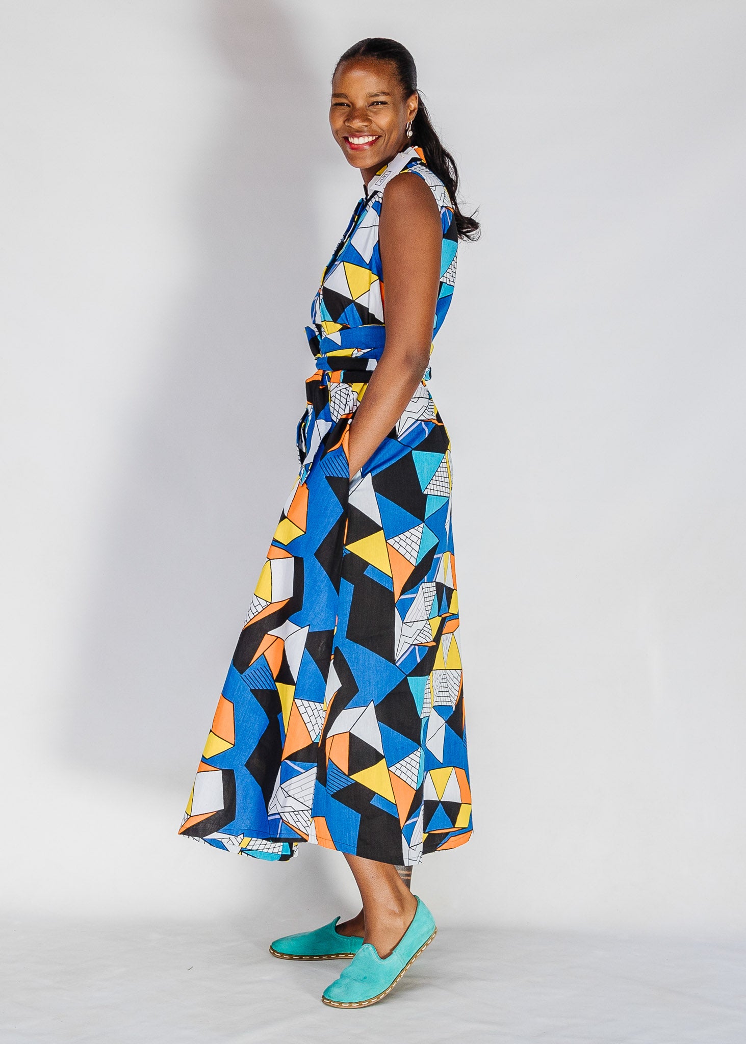 Model wearing blue dress with yellow, black, orange and white geometric print.