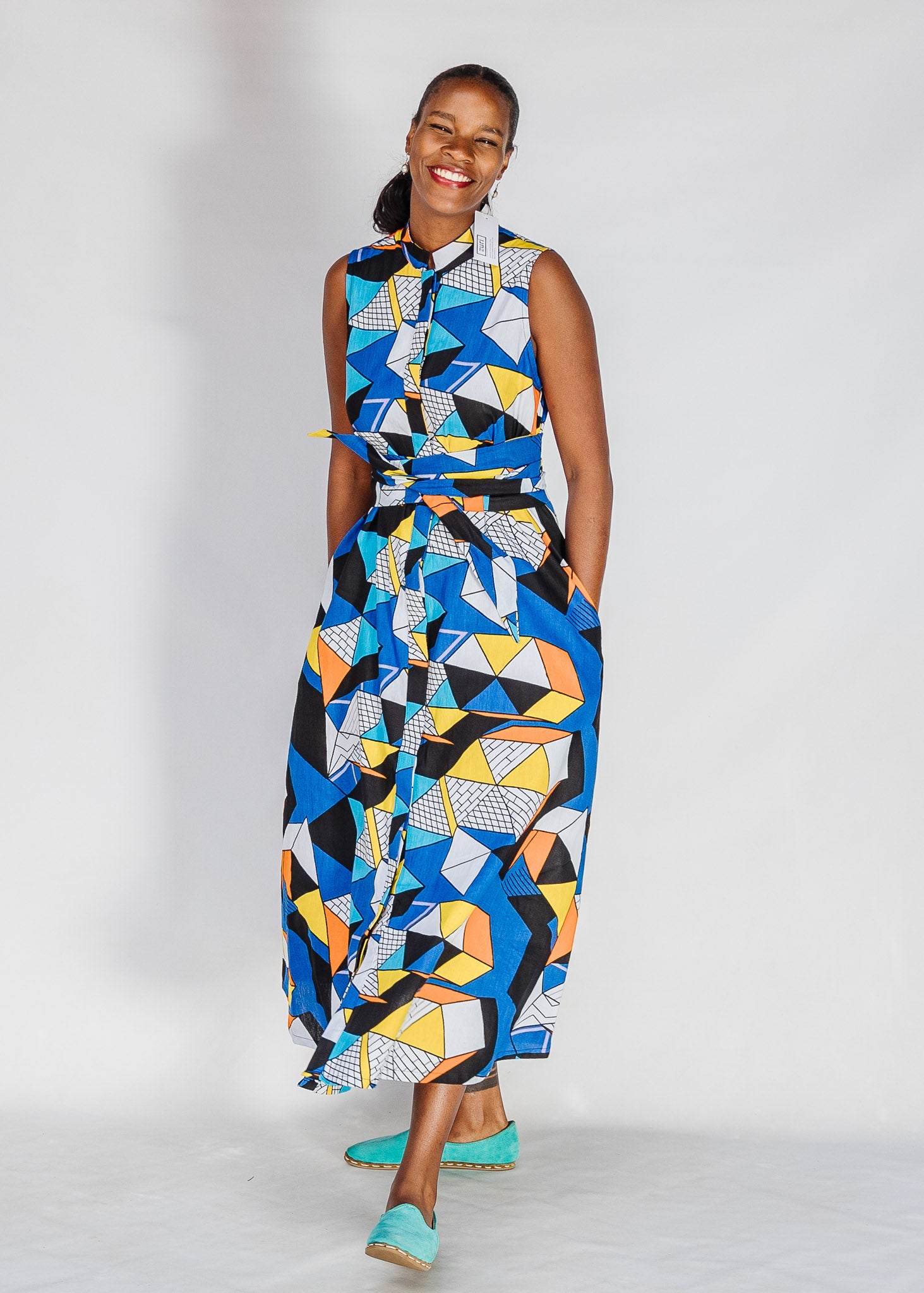 Model wearing blue dress with yellow, black, orange and white geometric print.