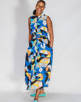 Model wearing blue dress with yellow, black, orange and white geometric print.