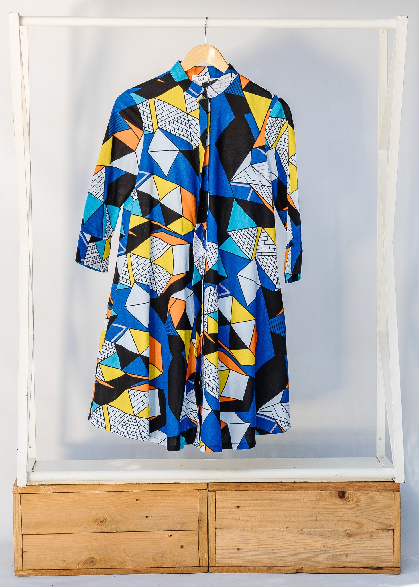 Display of blue dress with yellow, black, orange and white geometric print.