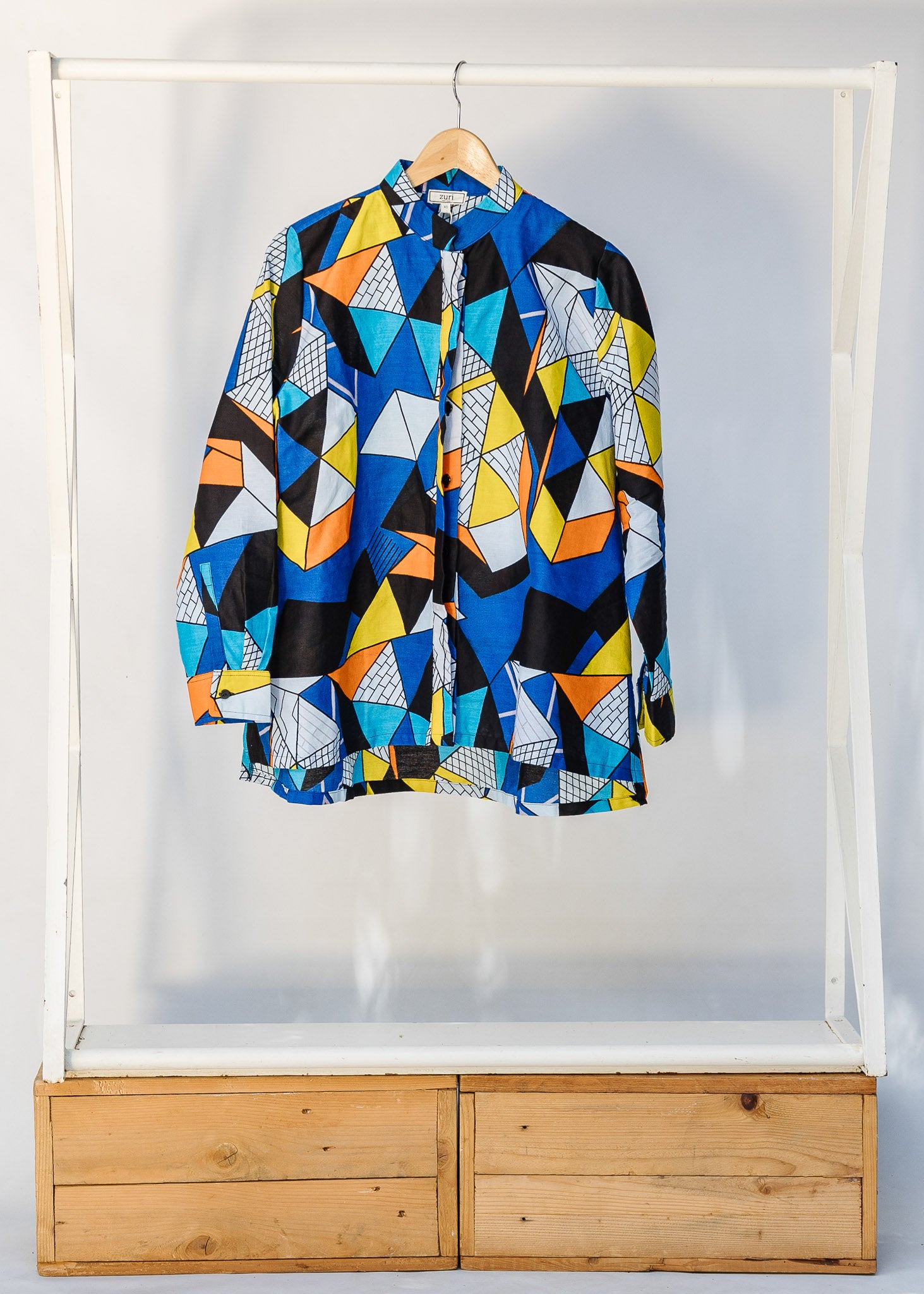 Display of blue, black, orange, yellow and white geometric print shirt.