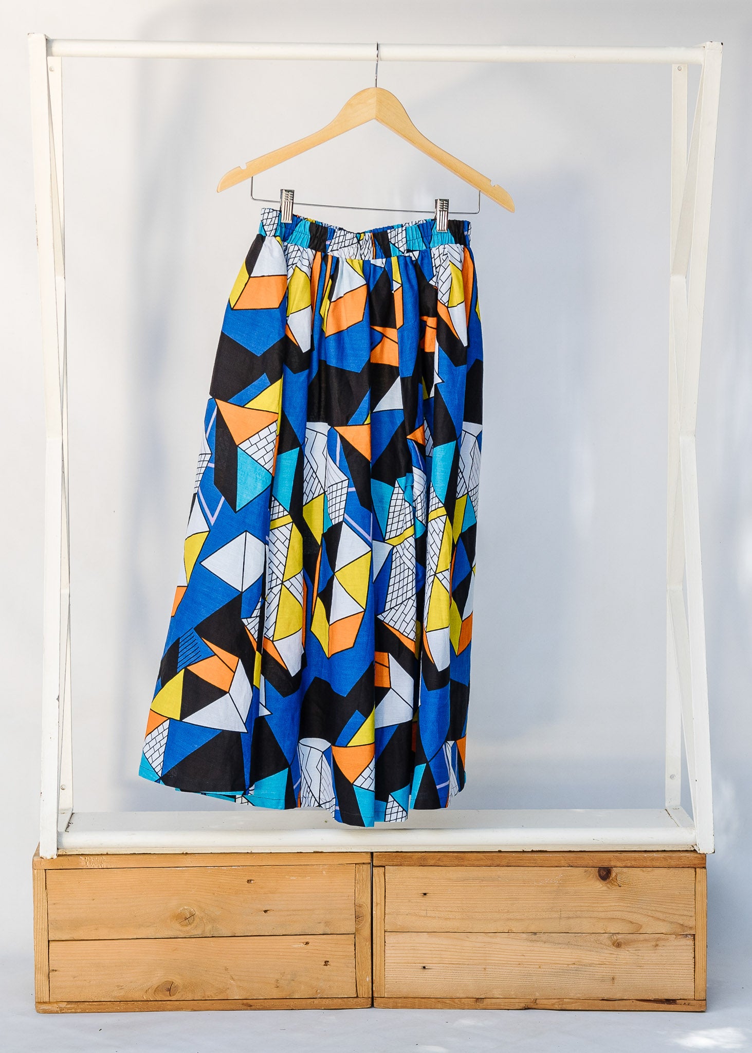 Display of blue, black, orange, yellow, orange and white geometric print shirt and culotte.