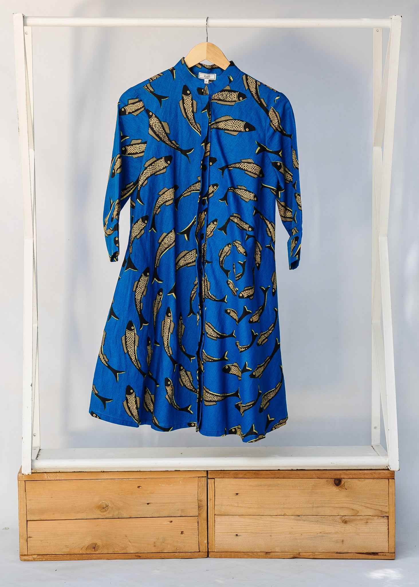 Display of blue dress with beige fish print.