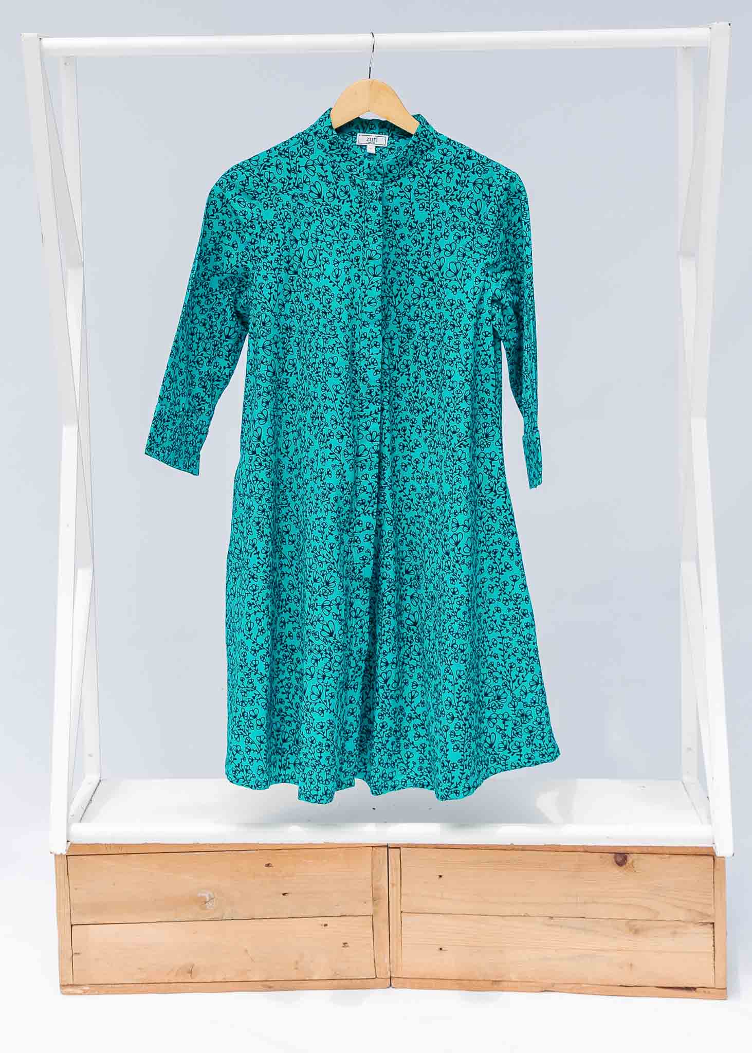 Display of turquoise dress with small black vine print.