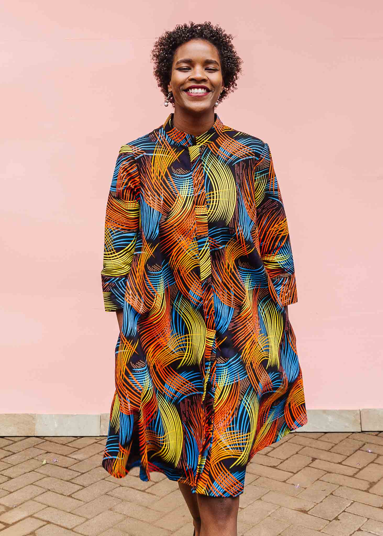 Model wearing black dress with rainbow brushstroke print.
