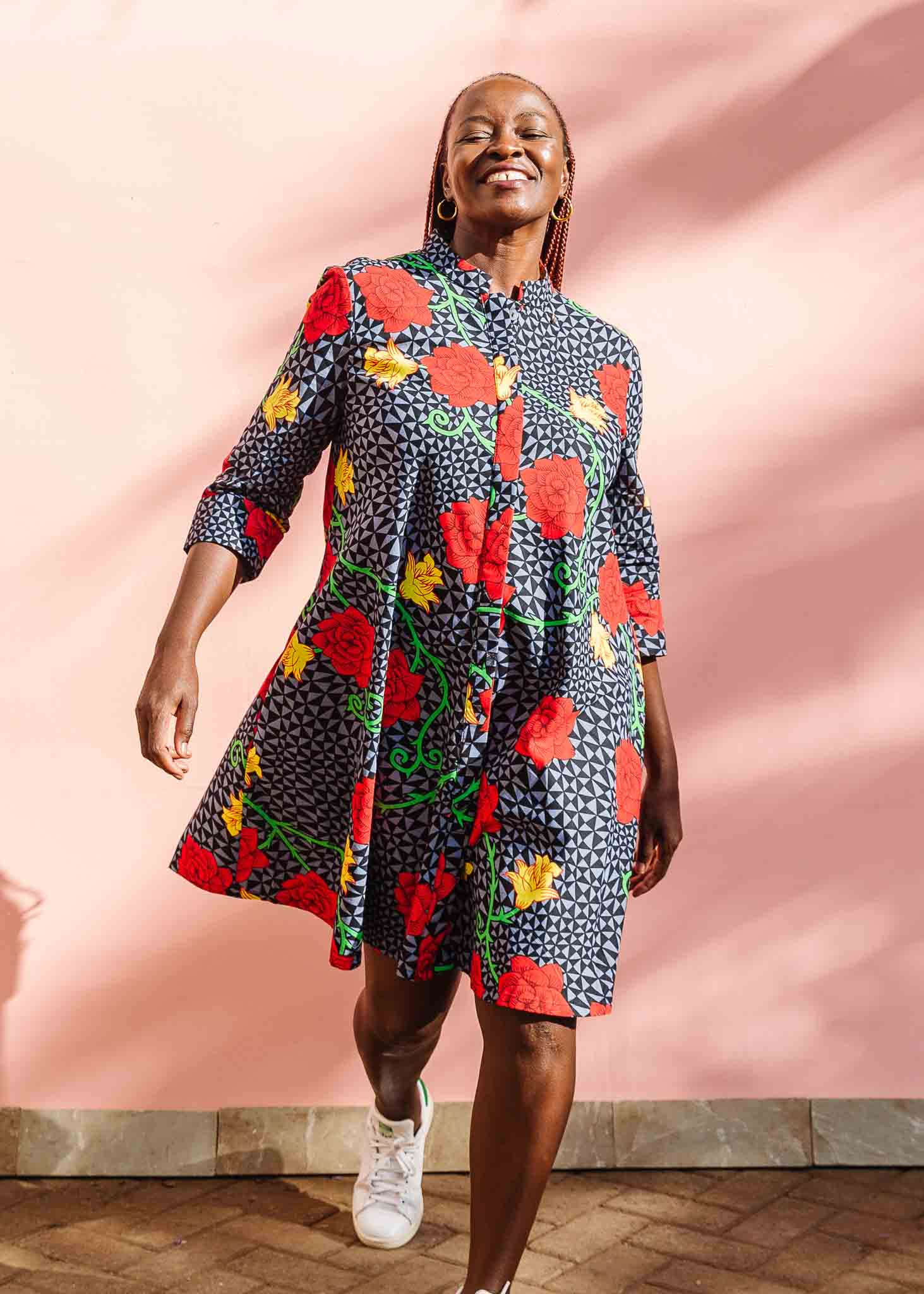 Model wearing gray and black dress with yellow and red rose print.