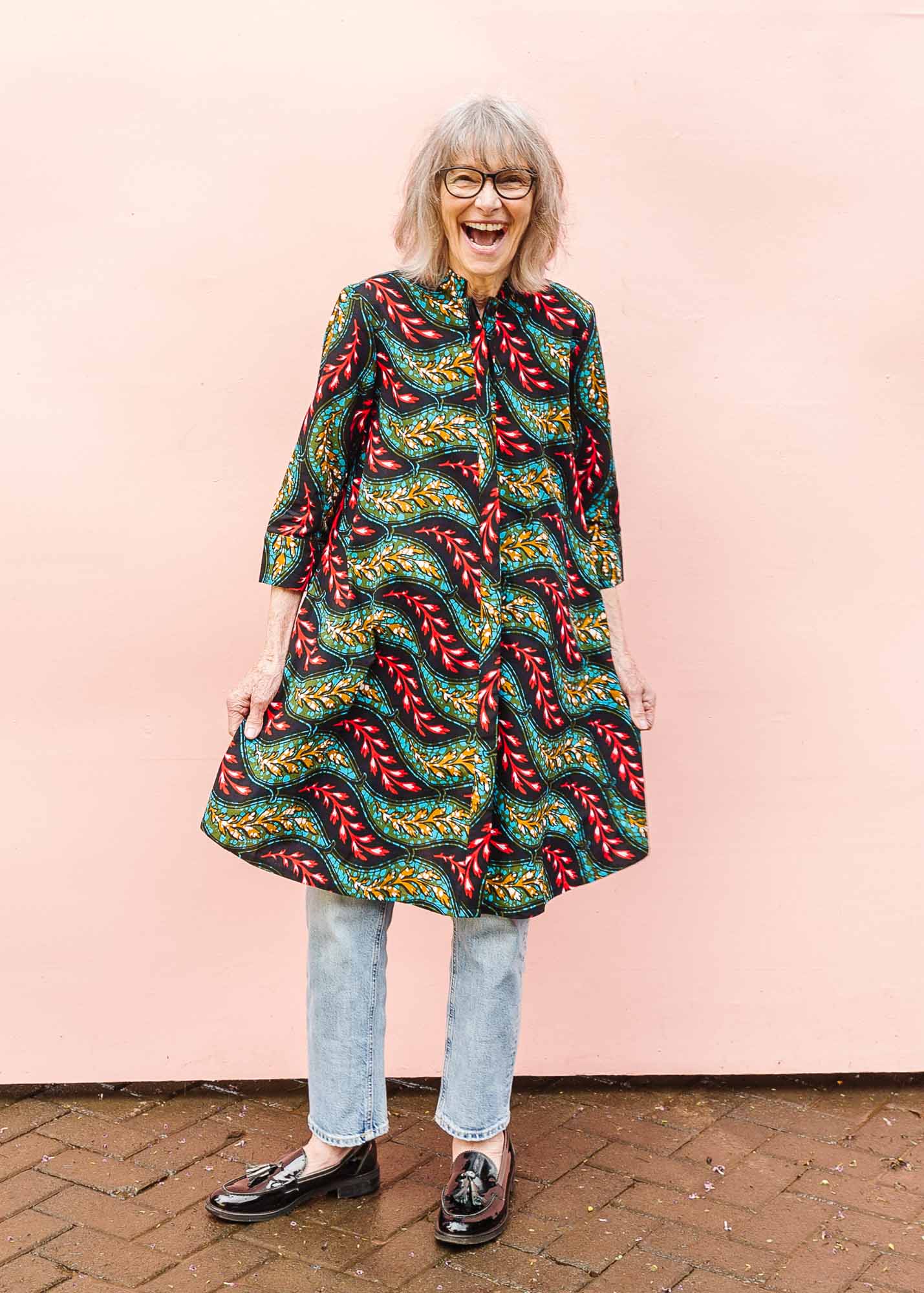 The model is wearing multicolored leaf print dress