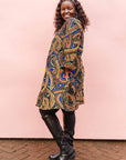 The model is wearing blue, red, black, yellow and white ornamental print dress 