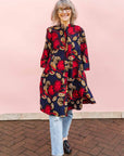 The model is wearing navy dress with red, white and orange floral print