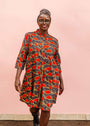 The model is wearing grey dress with red, yellow and black leaf print