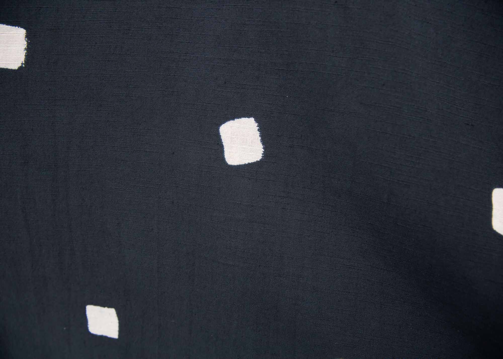 Close up display of solid black dress with white squares 