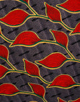 Close up display of grey dress with red, yellow and black leaf print, fabric