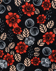 Close up display of black sleeveless shirt with red, grey and beige floral print, fabric.