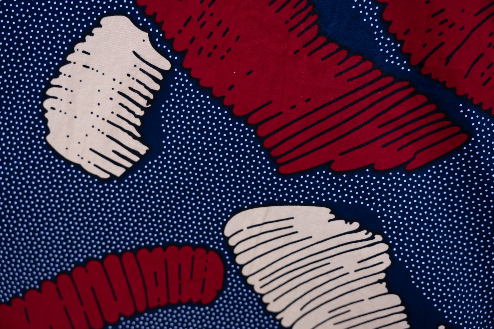 Close up display of navy sleeveless shirt with red and beige abstract print, fabric.