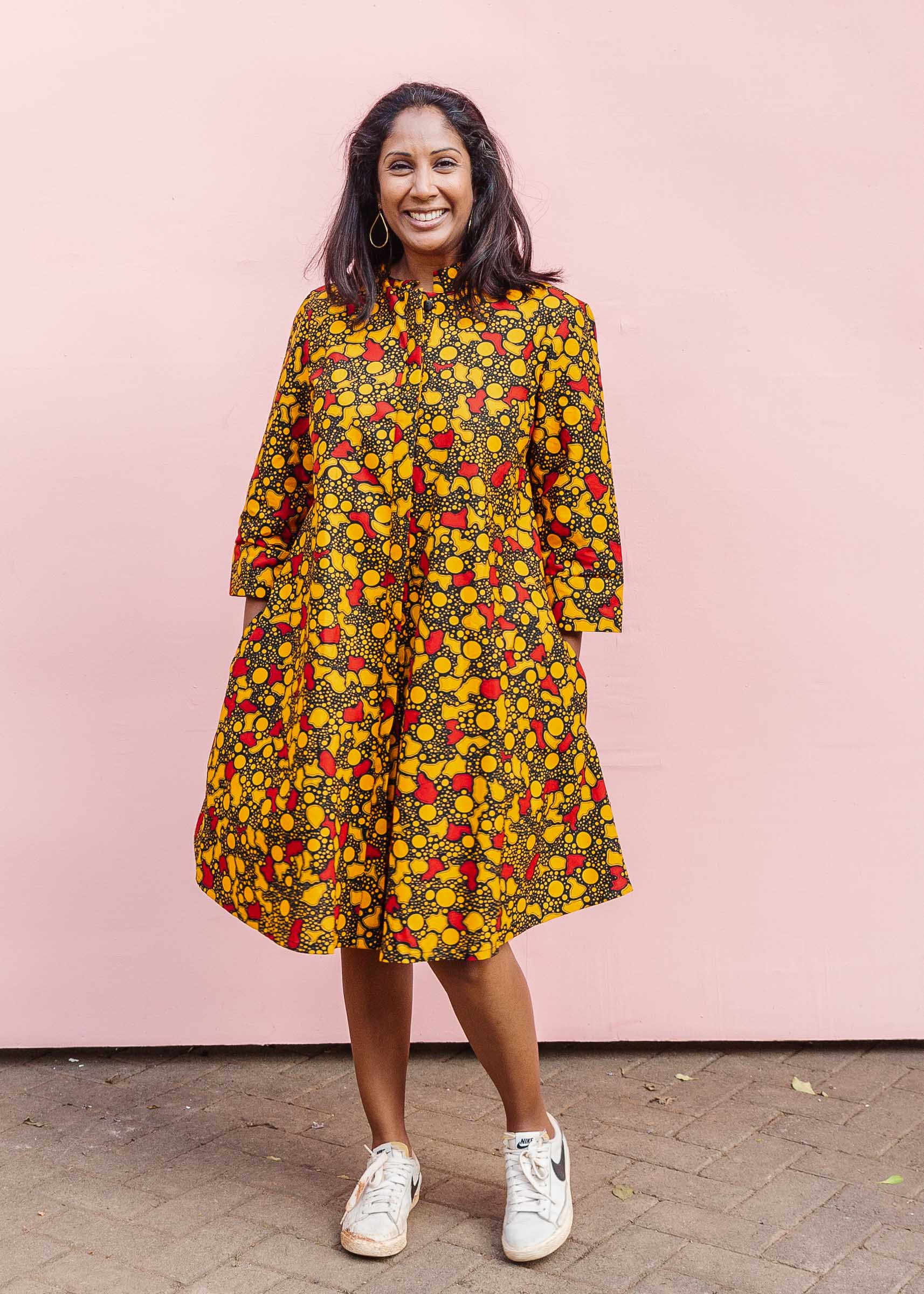 The model is wearing black dress with yellow and red small blob print.