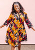The model is wearing black dress with yellow and pink floral print.
