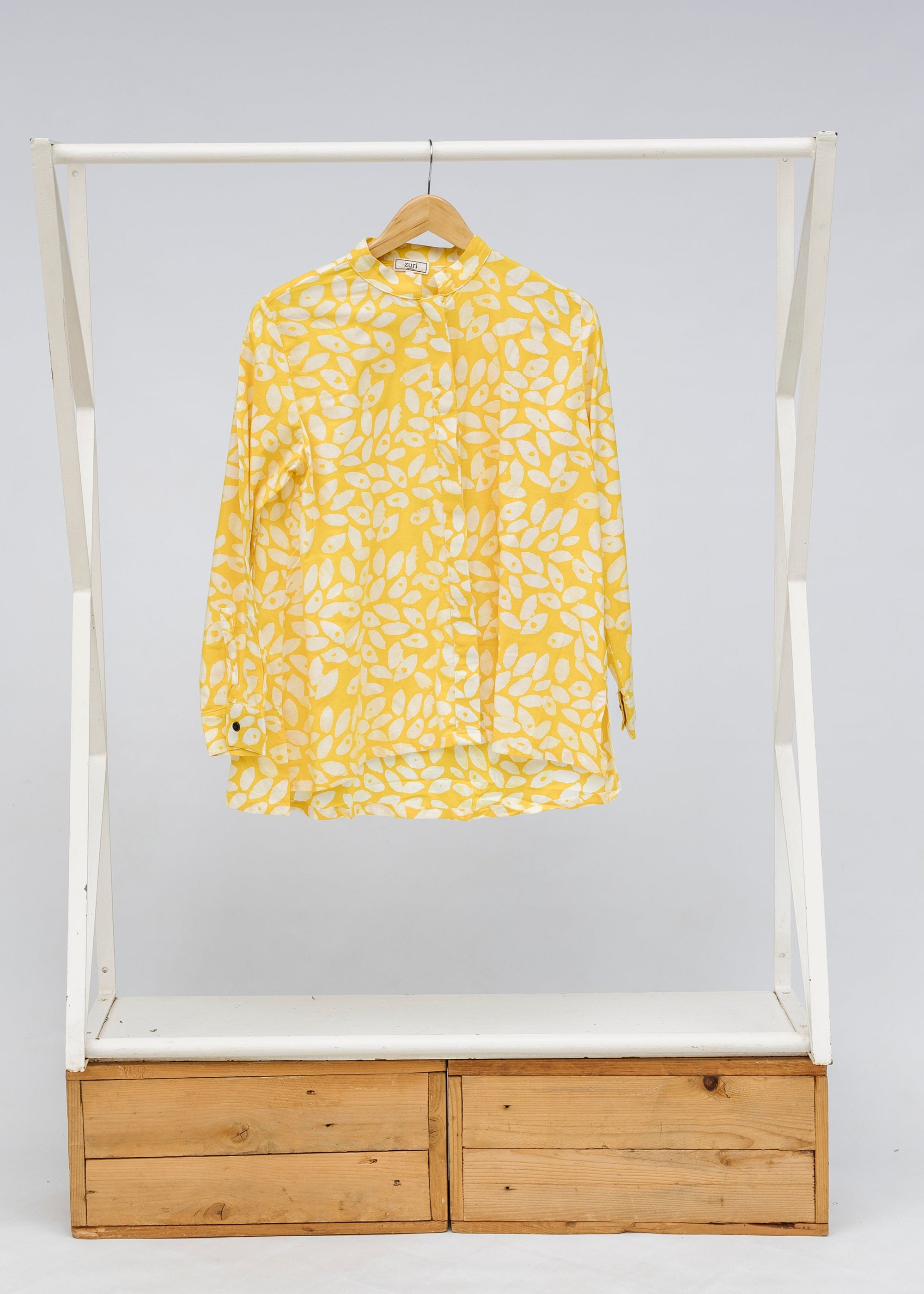 Display of yellow long sleeve shirt with white leaf print.