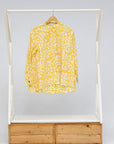 Display of yellow long sleeve shirt with white leaf print.
