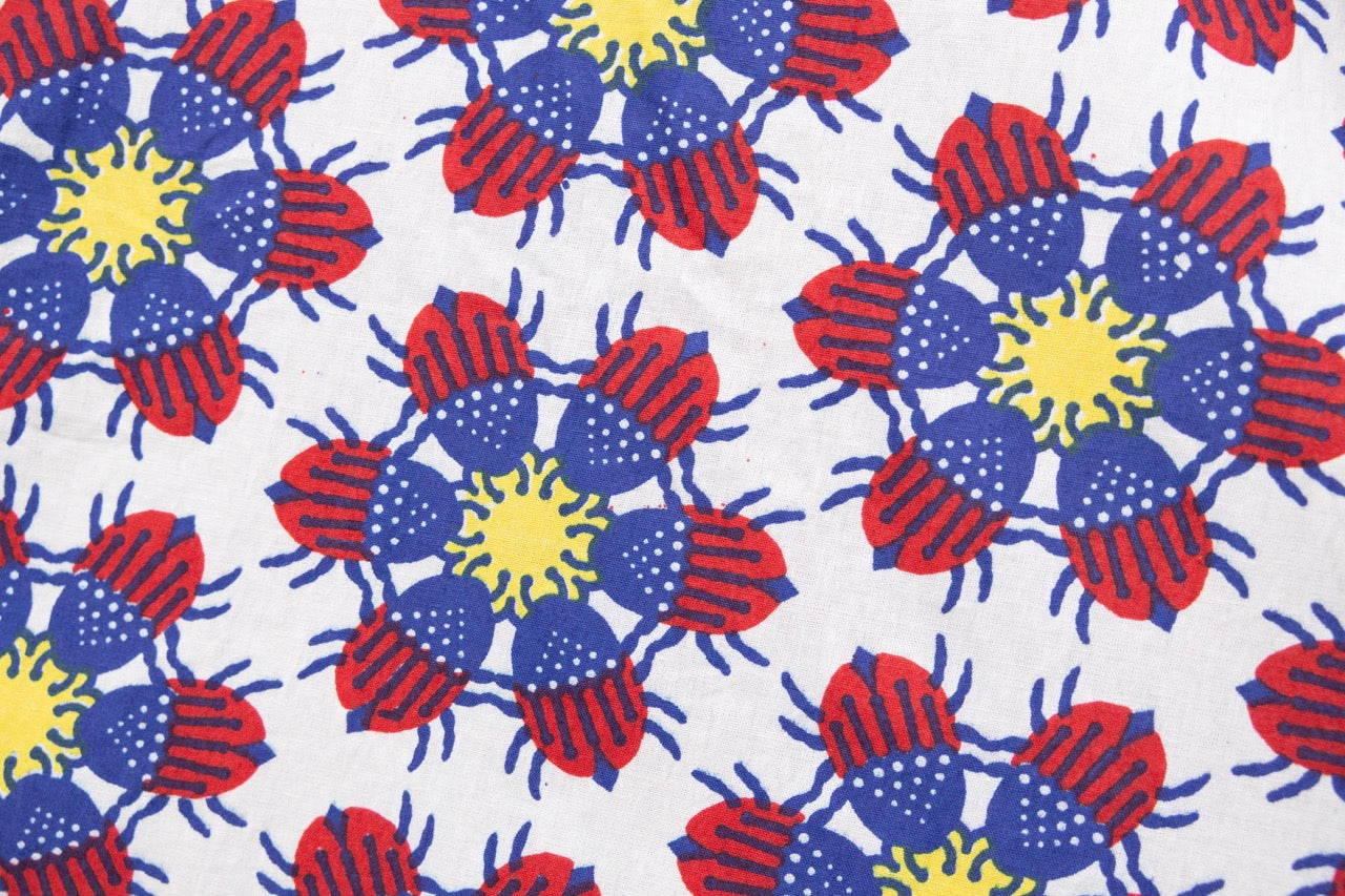 Close up display of white dress with yellow, red and blue bug print.