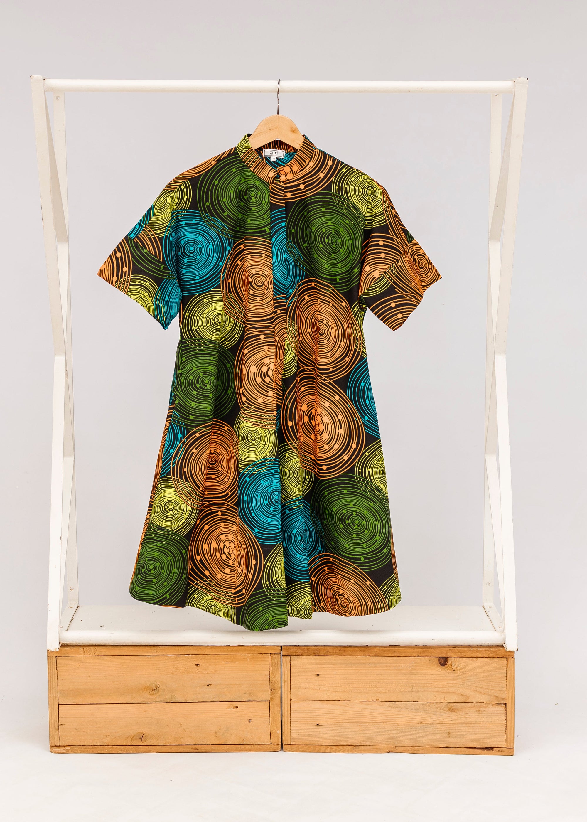 Display of black dress with orange, yellow, blue and green swirls.