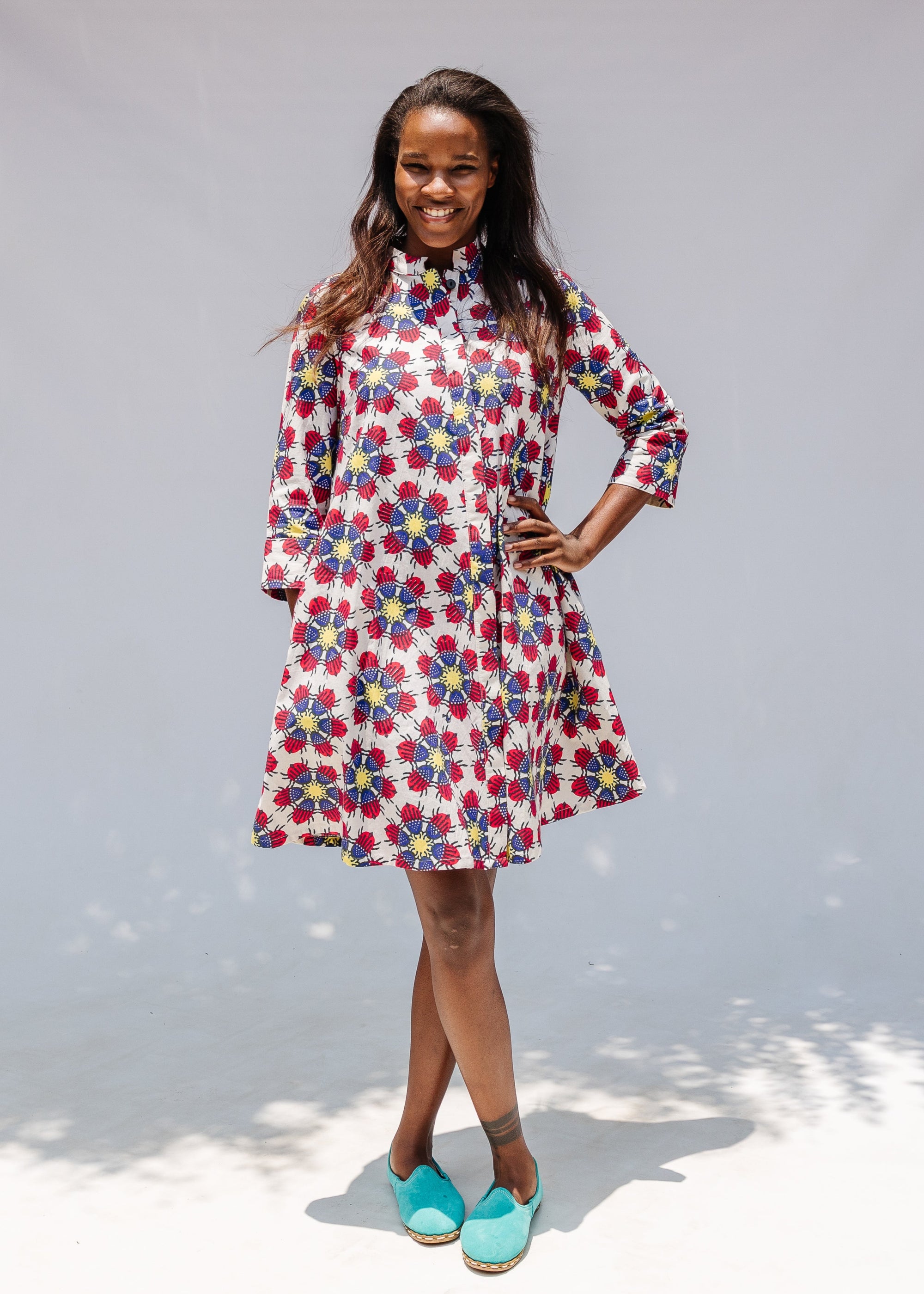 Model wearing white dress with yellow, red and blue bug print.