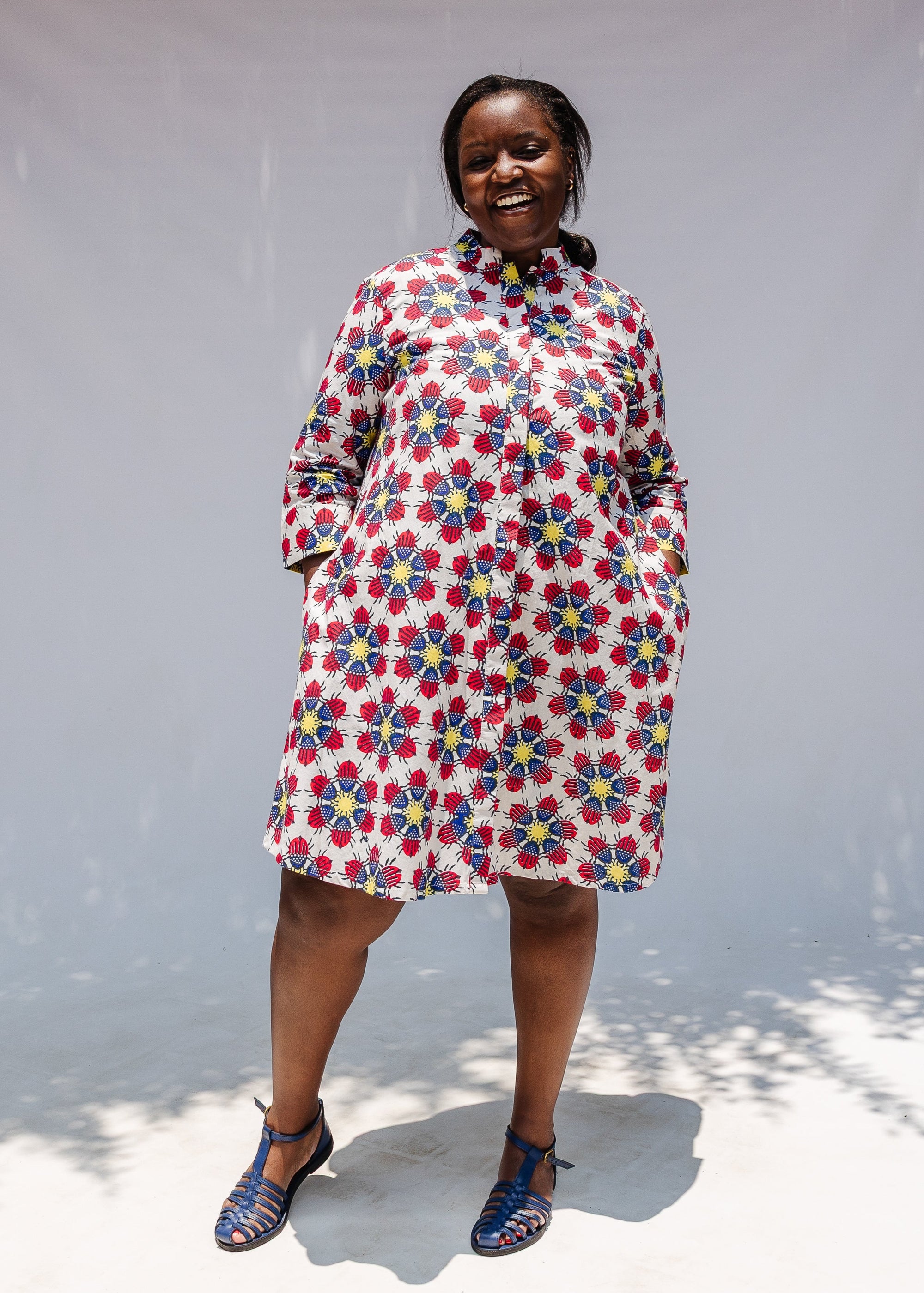 Model wearing white dress with yellow, red and blue bug print.