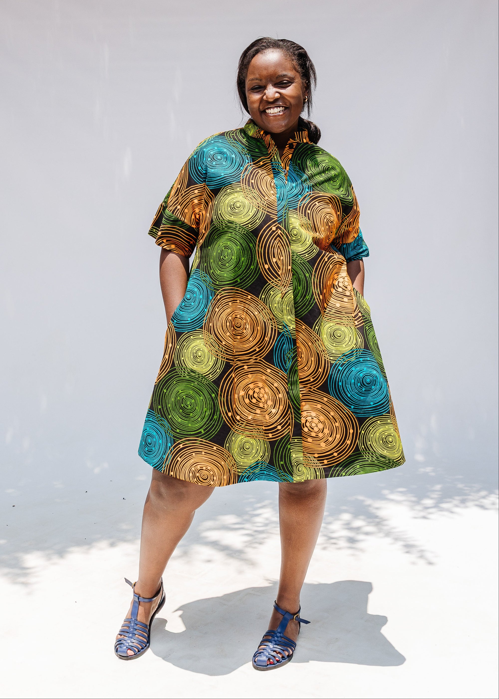 Model wearing black dress with orange, yellow, blue and green swirls.