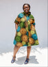Model wearing black dress with orange, yellow, blue and green swirls.