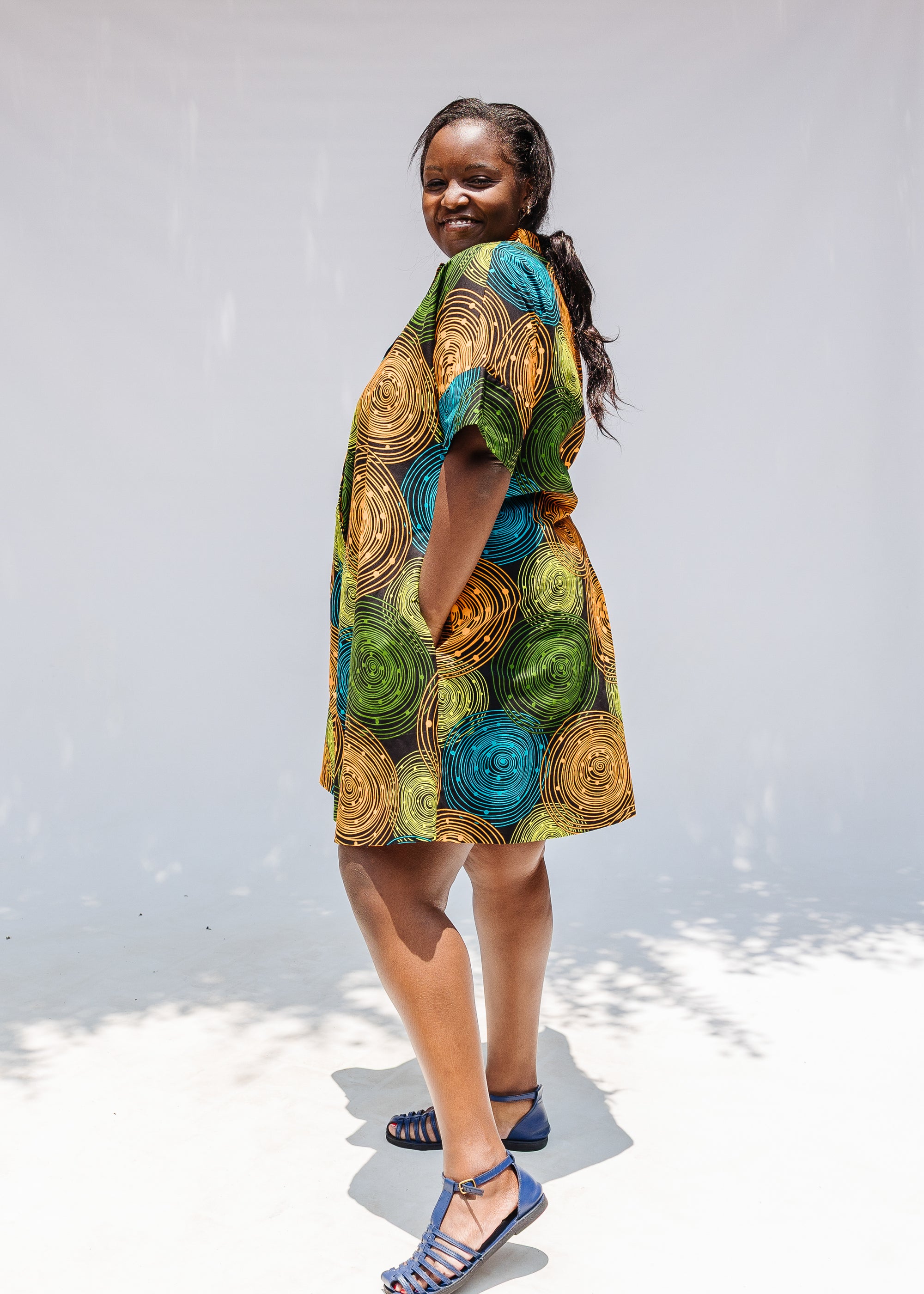 Model wearing black dress with orange, yellow, blue and green swirls.