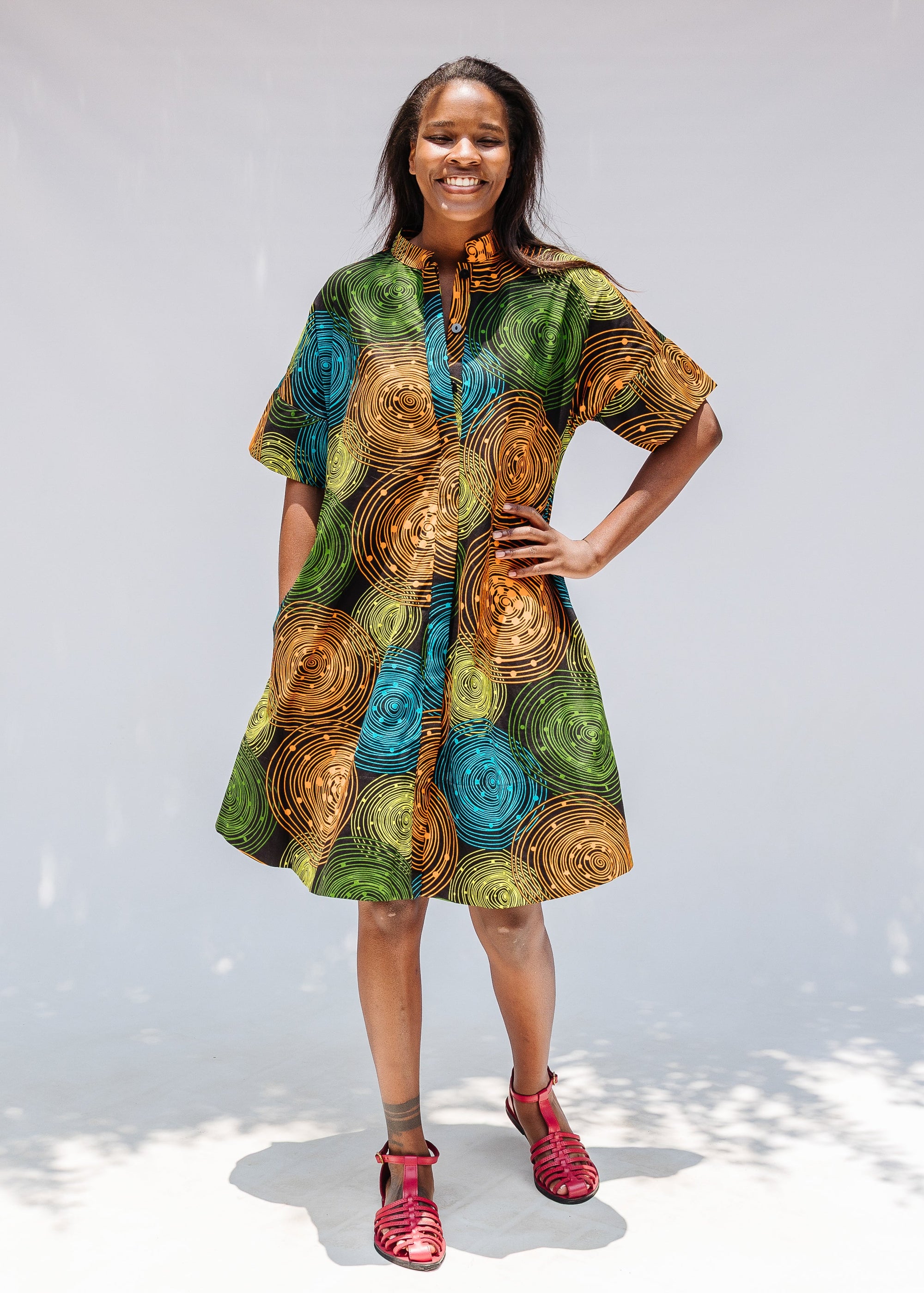 Model wearing black dress with orange, yellow, blue and green swirls.
