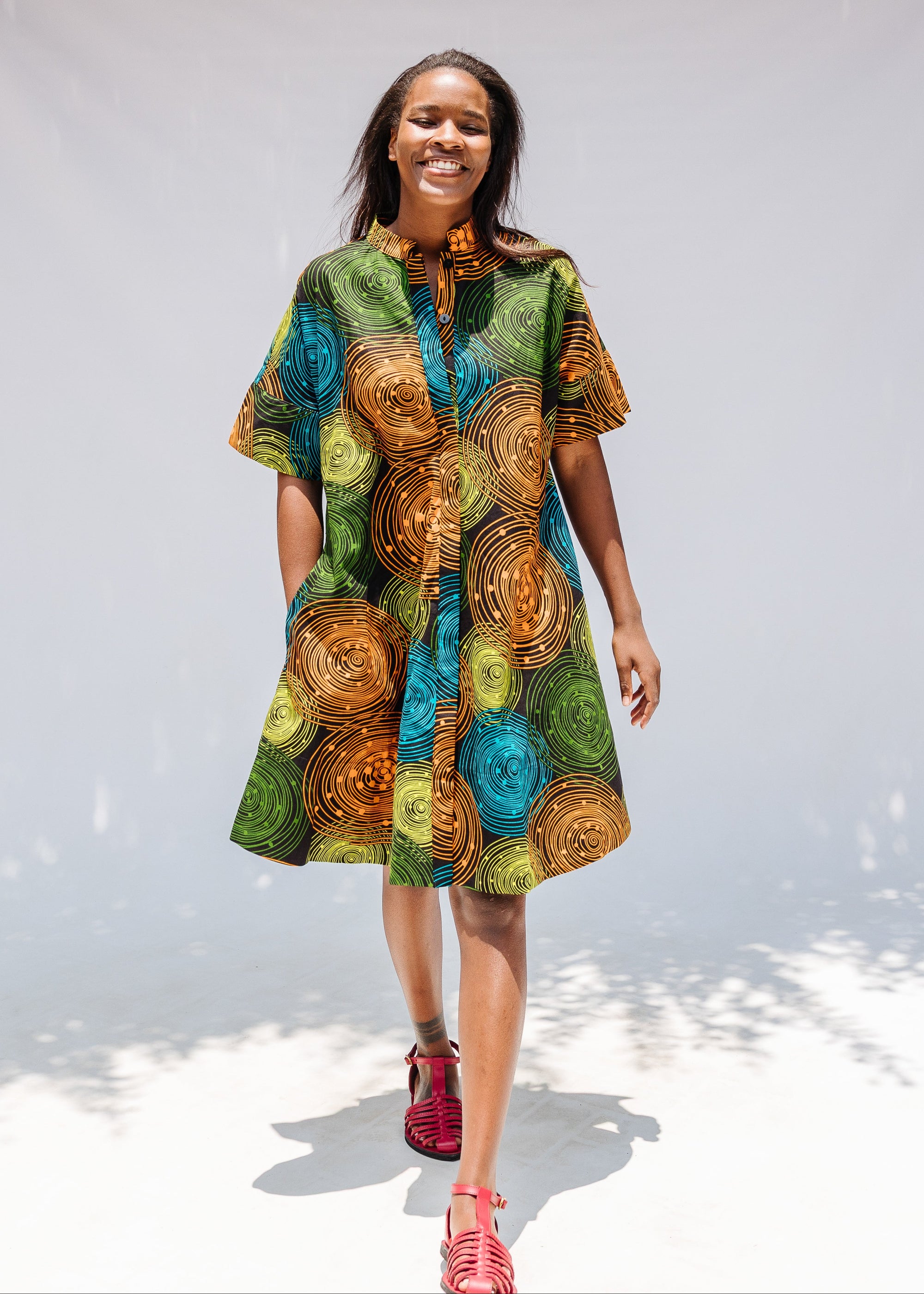 Model wearing black dress with orange, yellow, blue and green swirls.