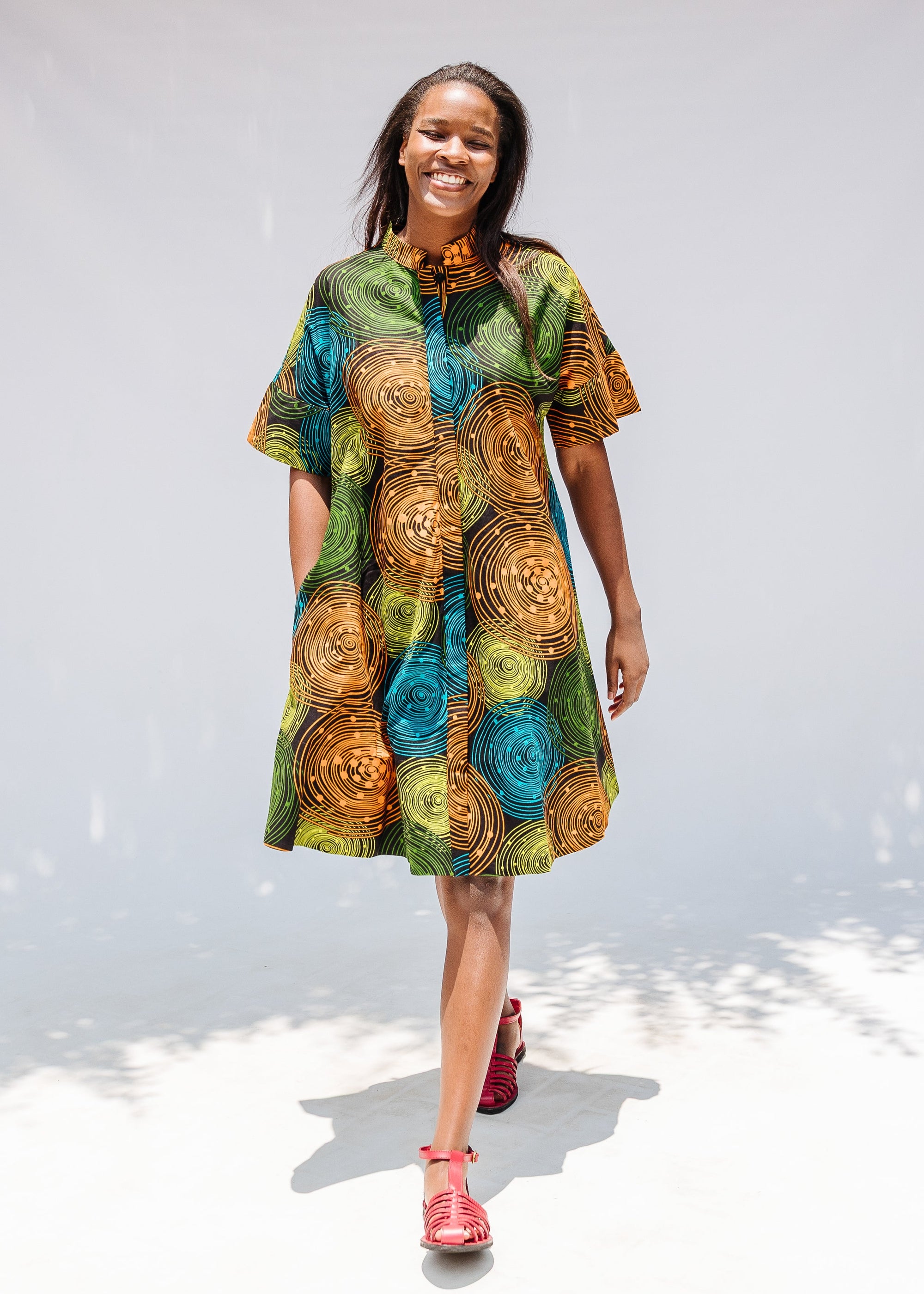 Model wearing black dress with orange, yellow, blue and green swirls.
