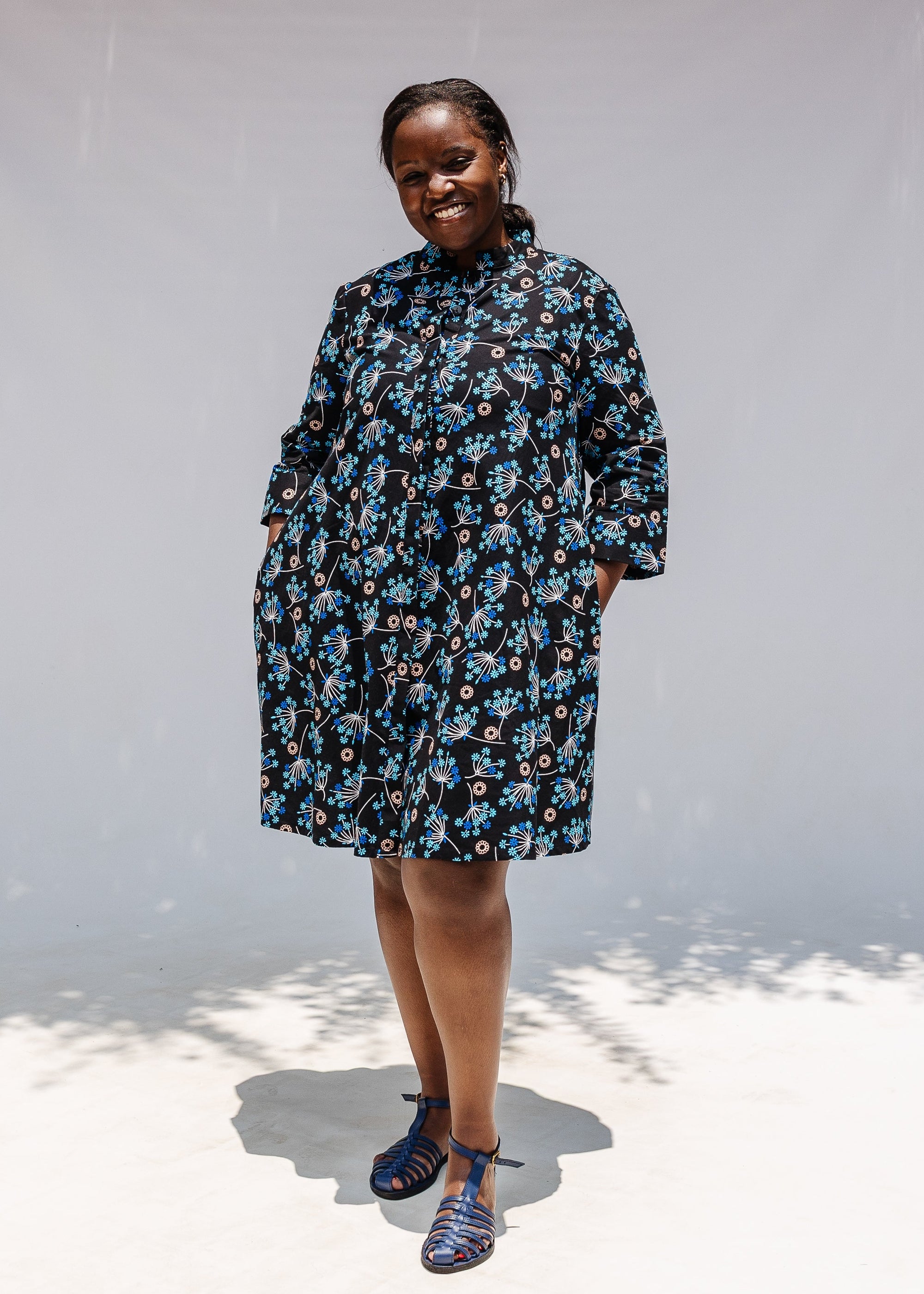 Model wearing black dress with blue and beige floral print.