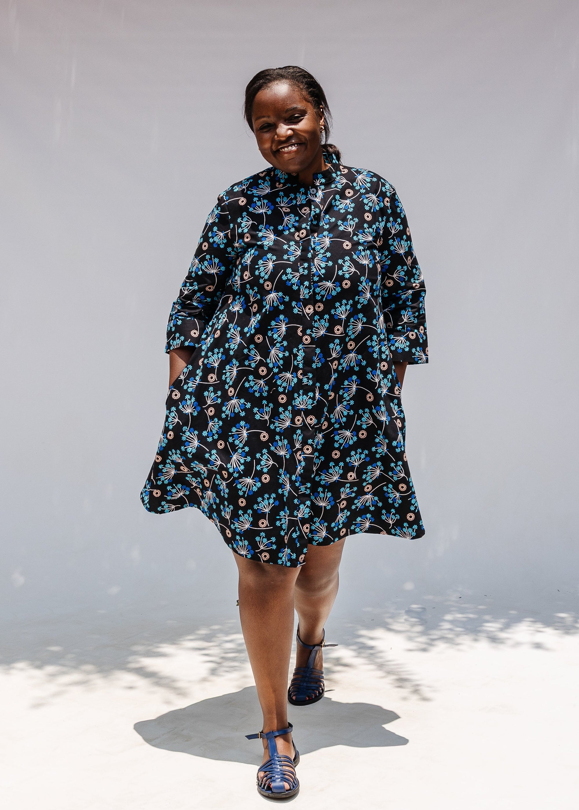 Model wearing black dress with blue and beige floral print.