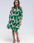 Model wearing green, black and white abstract print dress. 