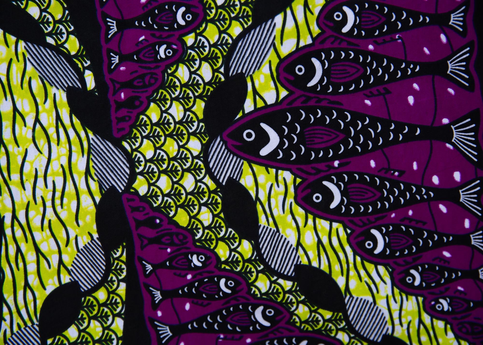 Close up display of yellow-green dress with purple, black, white fish print 