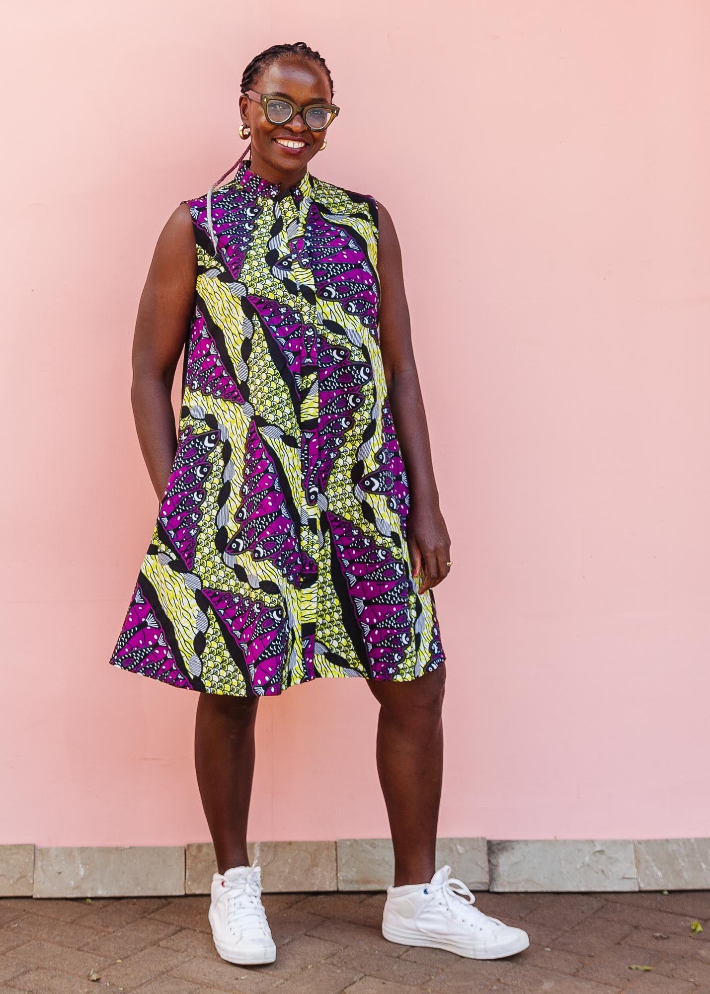 The model is wearing yellow-green dress with purple, black, white fish print 