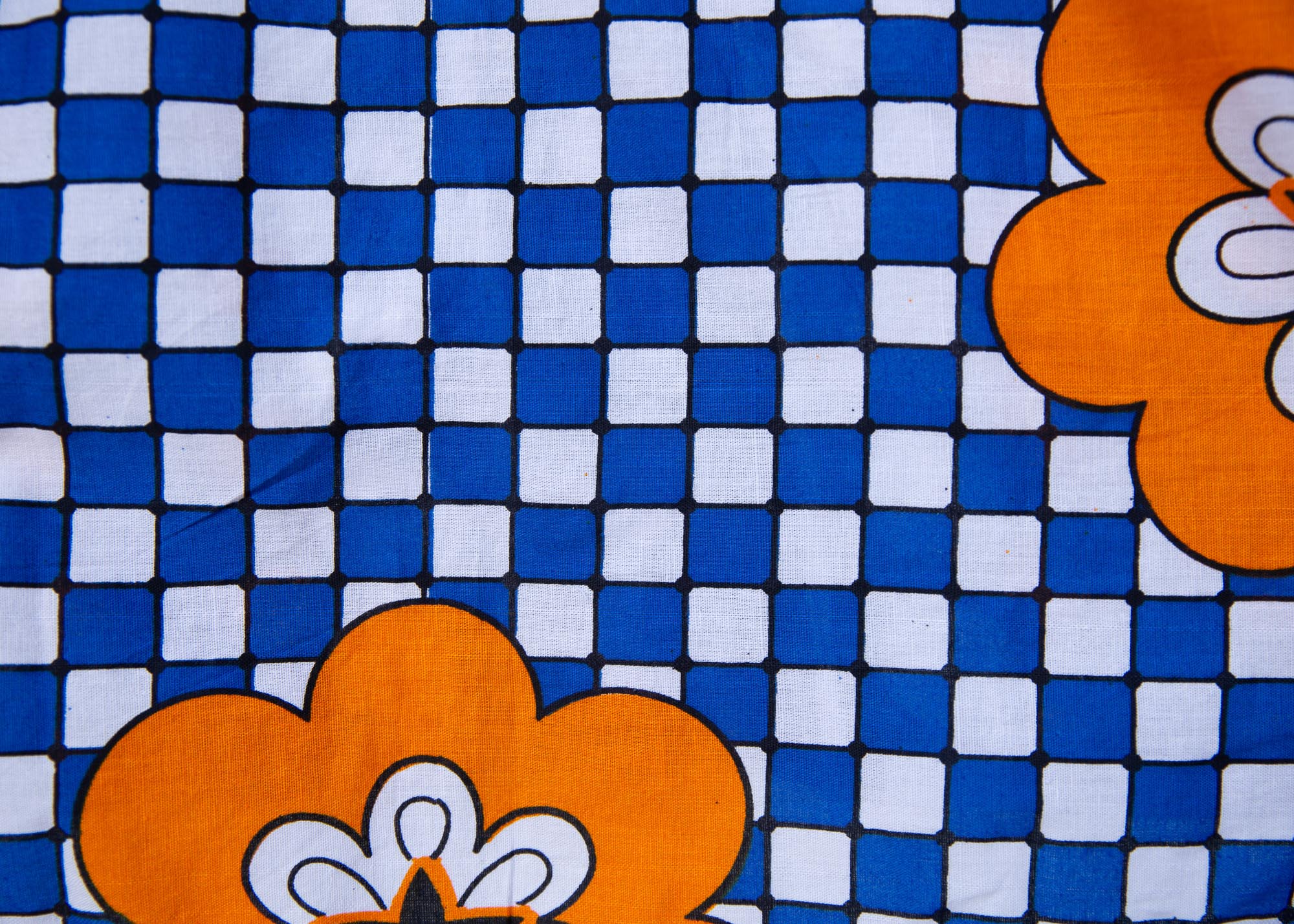 Close up display of black, white, orange and blue mixed pattern kanga shirt