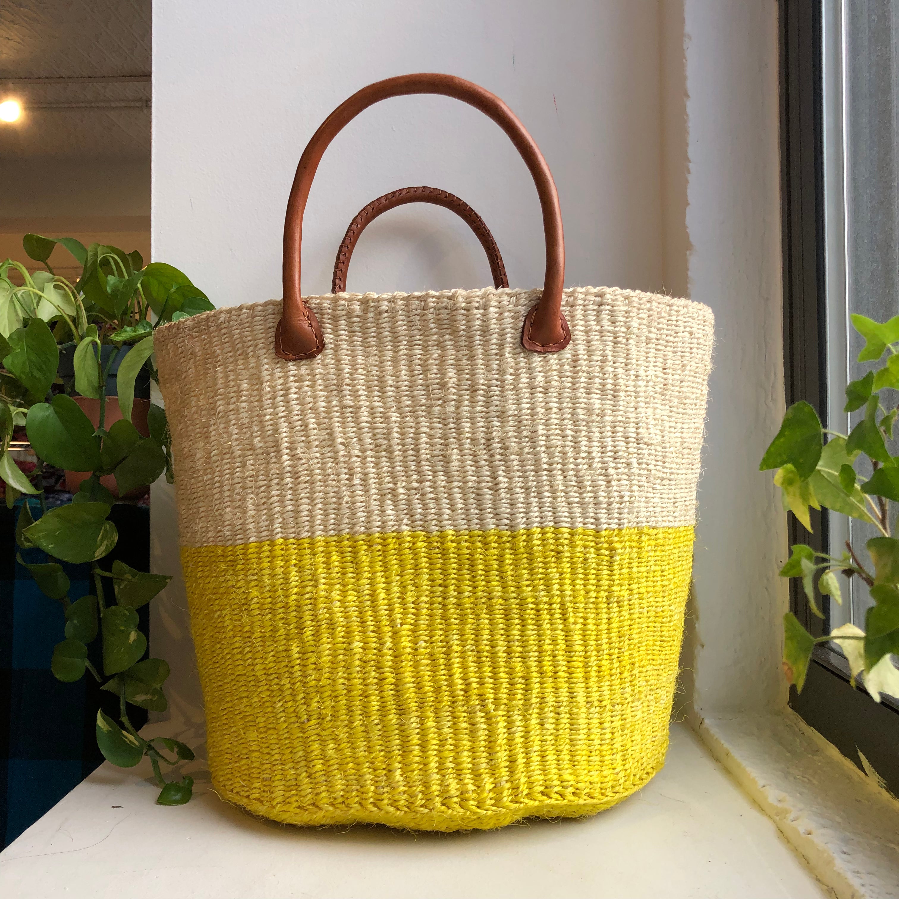 Yellow and white color block sisal woven basket with leather handles.