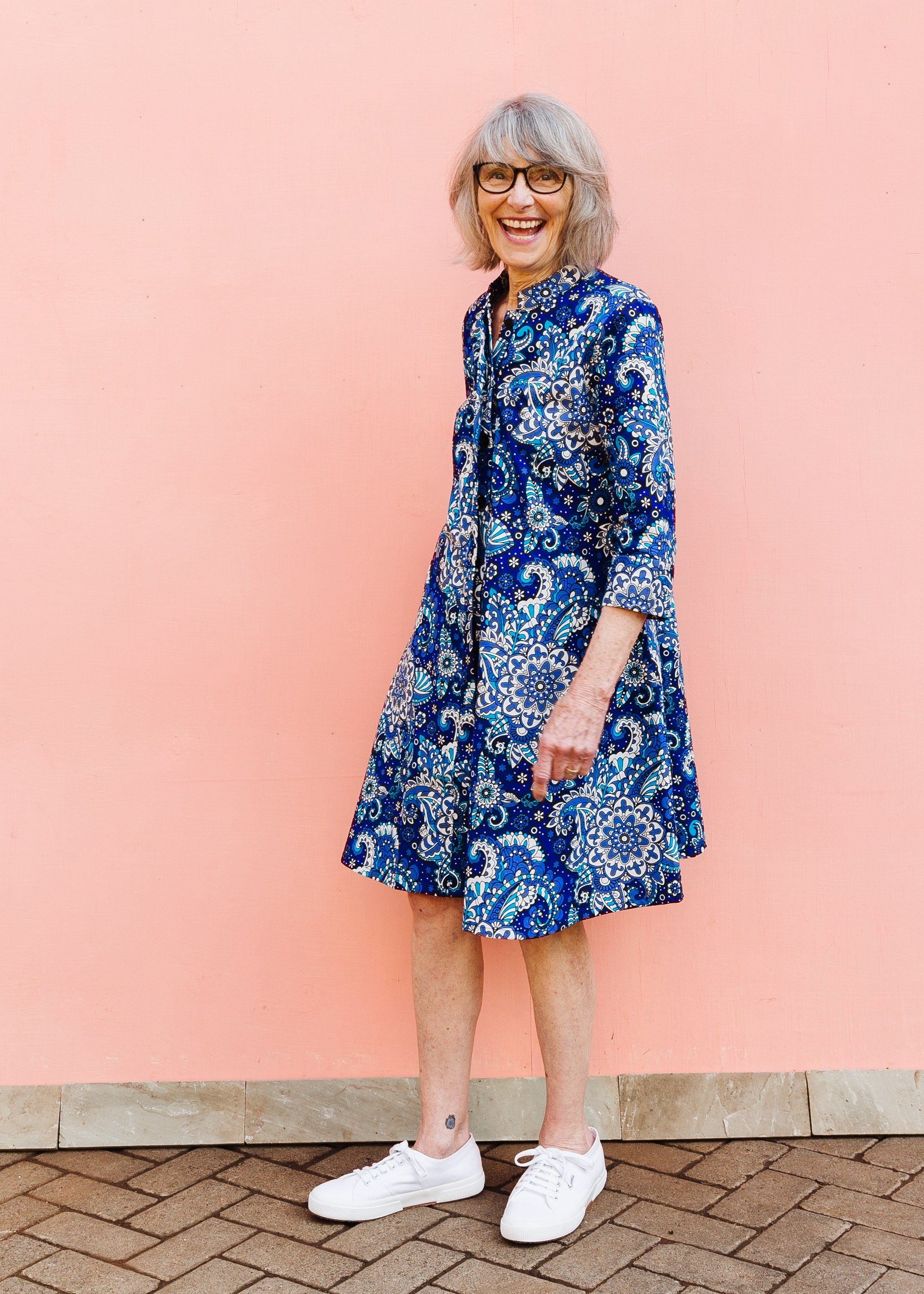 Model wearing blue paisley dress, paired with white sneakers.