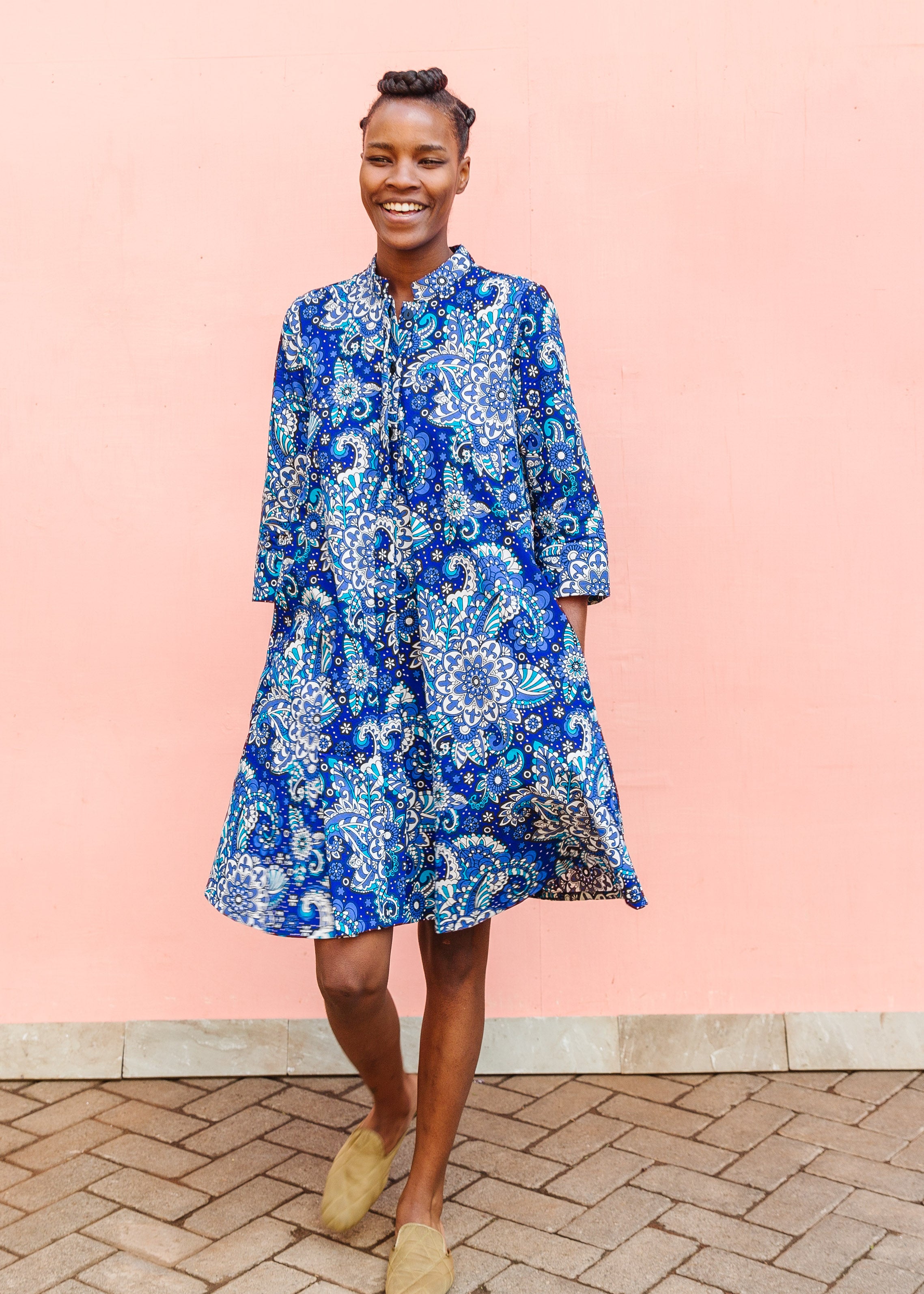 Model wearing blue paisley dress, paired with tan flats.
