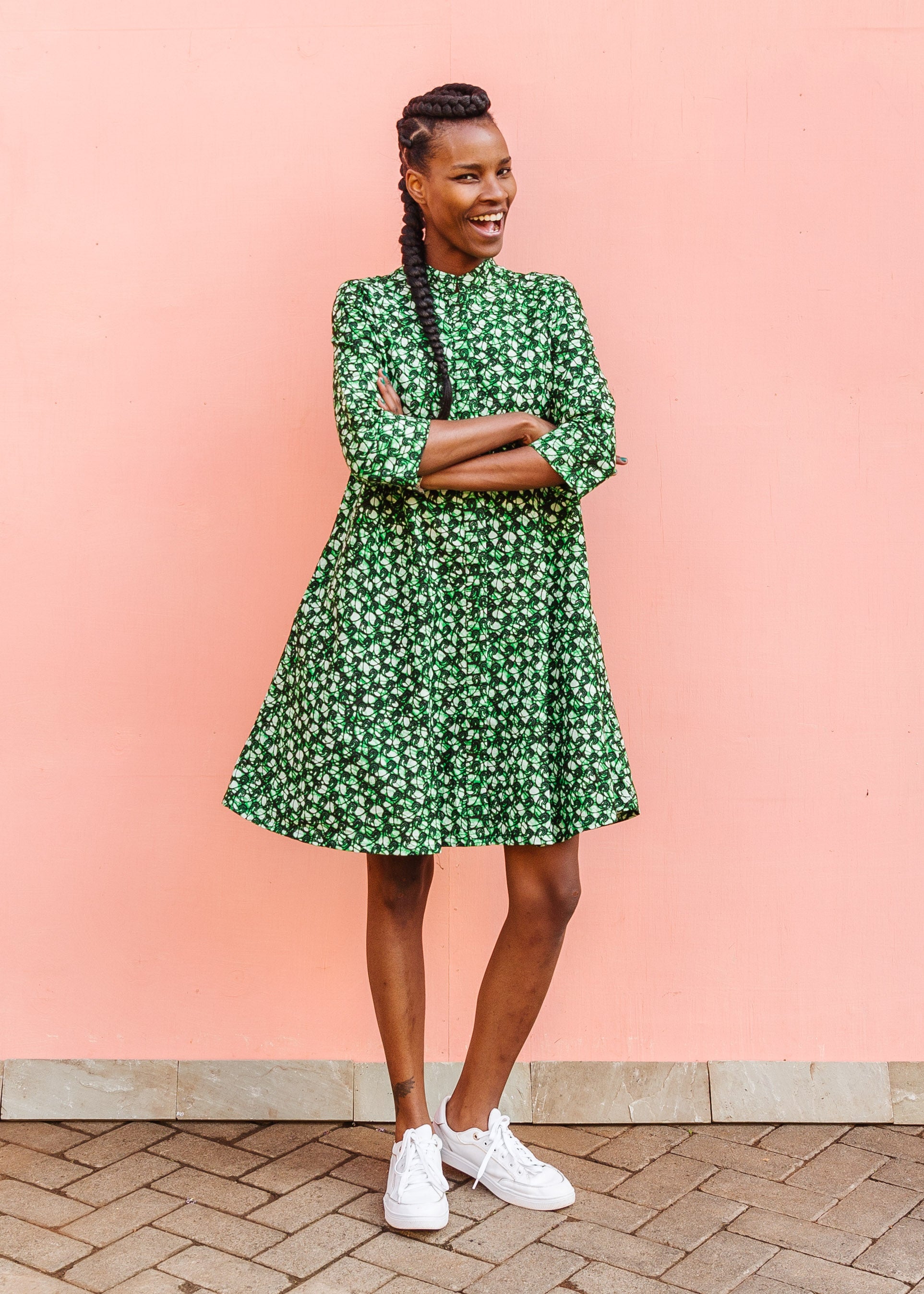Model wearing green paisley print dress, paired with white sneakers.