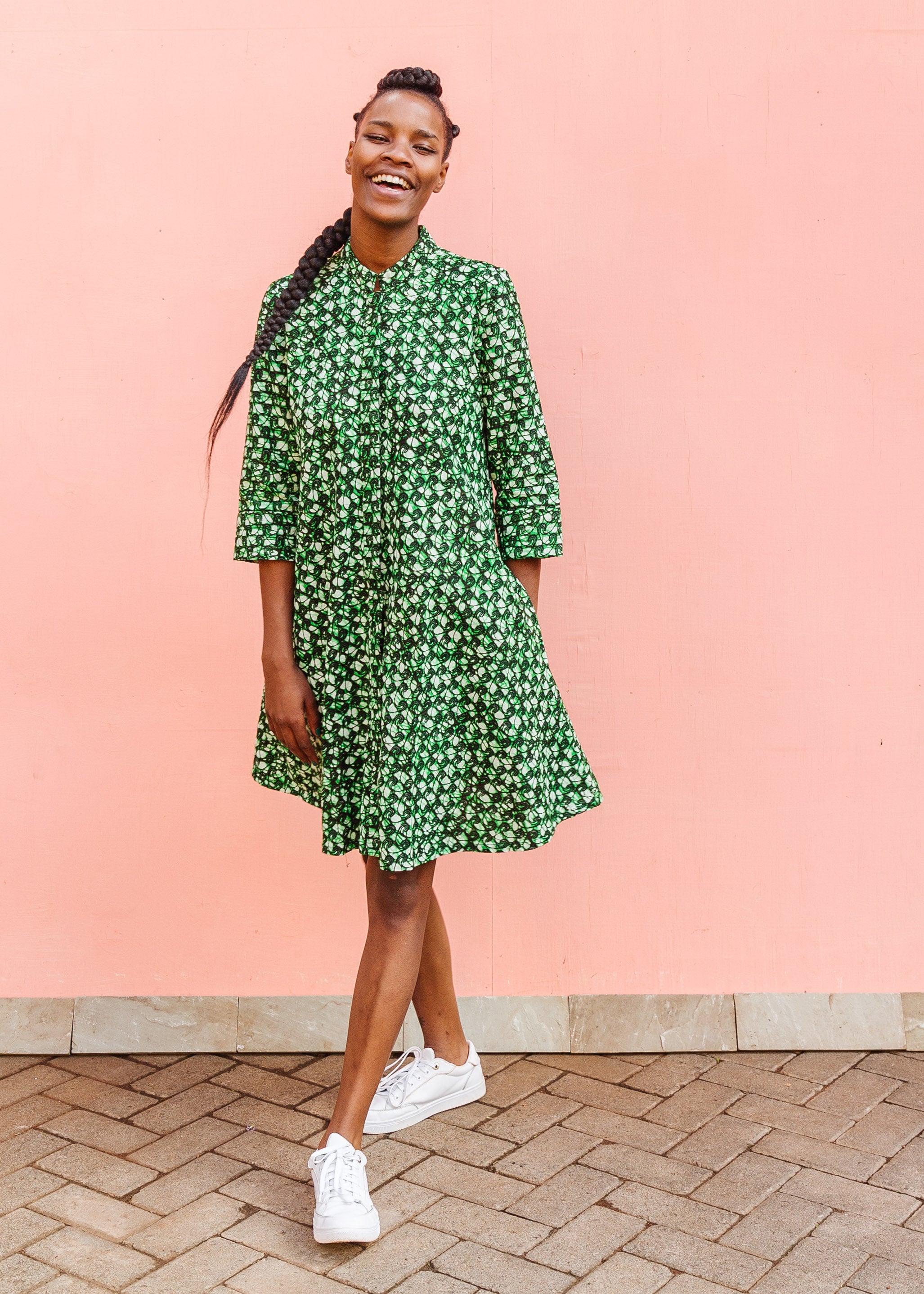 Model wearing green paisley print dress, paired with white sneakers.