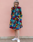 Model wearing rainbow dress with black boots.